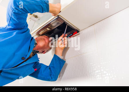 Mature workman fixing vent with worktool in kitchen Stock Photo