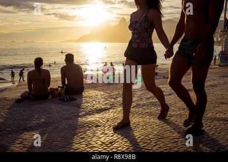 Scenic sunset silhouette view of people strolling on the Ipanema Beach promenade at Arpoador in Rio de Janeiro, Brazil Stock Photo