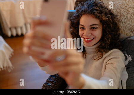 Smiling beautiful young woman with curly hair is taking a self-portrait Stock Photo