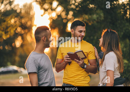 Three friends are outdoors argueing about directions in the park Stock Photo
