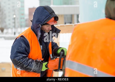 Work installer in a protective helmet and reflective vest with a chainsaw in profile Stock Photo
