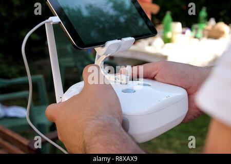 Professional photographer and drone pilot holds remote control panel with screen and controls ready to fly quad copter in air to see birds point. Stock Photo