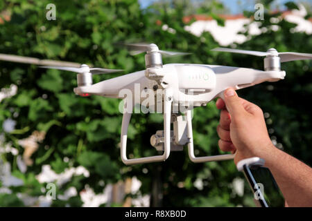 Man is holding a drone in hand and using of new technology. White quad copter Drone and photographer man hands. Professional drone pilot holds panel. Stock Photo