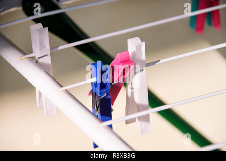 Cloth Clothespins on drying rack, selective focus. Colorful plastic clothespins on clothesline. A lot of multicolored wool cloth clamps attached. Stock Photo