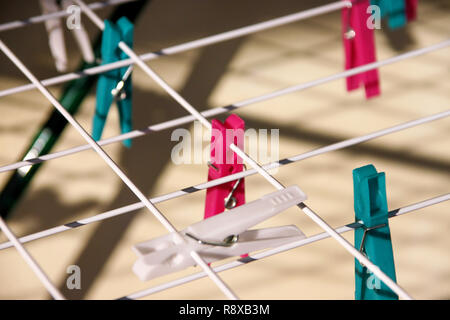 Cloth Clothespins on drying rack, selective focus. Colorful plastic clothespins on clothesline. A lot of multicolored wool cloth clamps attached. Stock Photo