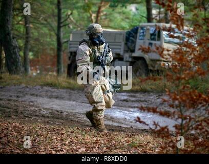 A U.S. Army Soldier assigned to the Brigade Headquarters for the 1st Armored Brigade Combat Team, 1st Cavalry Division moves forward in full MOPP gear while coming under simulated gas attack during exercise Combined Resolve XI in Hohenfels, Germany, Dec. 7, 2018. CBRXI at the Joint Multinational Readiness Center is the final exercise in 1-1 CD’s rotation in support of Atlantic Resolve in Europe, which evaluates the interoperability of U.S. Forces with their NATO allies and partners. Stock Photo