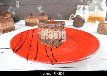 Triple chocolate cake with creamy chocolate layer on a red plate. Stock Photo