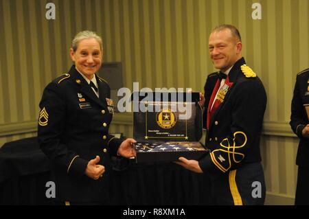 Sgt. 1st Class Diana Moyers-Siebels, one of four remaining female Soldiers to have entered the Army through the Women’s Army Corps program, receives her retirement flag from Col. Michael Roache, 646th Regional Support Group commander. Stock Photo