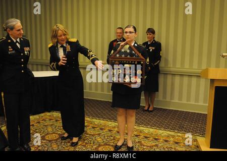 Sgt. 1st Class Diana Moyers-Siebels, one of four remaining female Soldiers to have entered the Army through the Women’s Army Corps program, receives a shadow box documenting her Army career from Lt. Col. Nancy McCoy, 646th Regional Support Group Staff Judge Advocate during a retirement ceremony at a 646th RSG Dining Out. Stock Photo