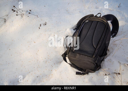 Black backpack is in the snow, comfortable heavy backpack Stock Photo