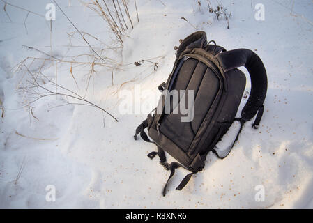 Black backpack is in the snow, comfortable heavy backpack Stock Photo