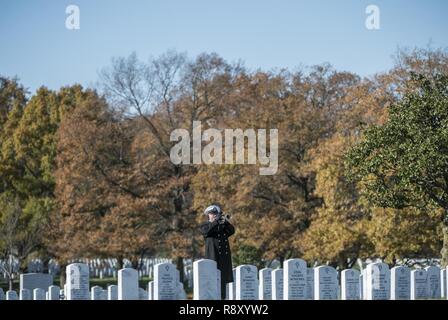 A bugler from the U.S. Navy Band sounds 'Taps' as part of military funeral honors with funeral escort for U.S. Navy Seaman 1st Class William Bruesewitz in Section 60 of Arlington National Cemetery, Arlington, Virginia, Dec. 7, 2018. On Dec. 7, 1941, Bruesewitz was assigned to the battleship USS Oklahoma which was moored at Ford Island, Pearl Harbor when the ship was attacked by Japanese aircraft. After sustaining multiple torpedo hits, the USS Oklahoma quickly capsized and resulted in the deaths of 429 crewmen, including Bruesewitz.    From the Defense POW/MIA Accounting Agency (DPAA) new rele Stock Photo