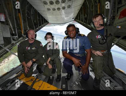 Fijian navy Sub-Lt. Opeti Enesi, a navigation officer, and an Air Station Barbers Point HC-130 Hercules aircrew fly over the Fijian islands, Dec. 8, 2018. Enesi was acting as a shiprider for the Fiji government during a joint law enforcement operation. Stock Photo