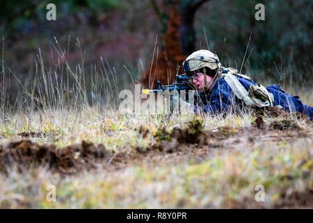 A member of the opposing forces working under the 7th Army Training Command, takes a prone position in order to accurately and effectively engage enemies during a training mission as part of exercise Combined Resolve XI in Hohenfels Training Area, Germany, Dec. 7, 2018.    CBRXI gives the U.S. Army’s regionally allocated forces in Europe the opportunity to execute a combat training center rotation with a joint, multinational environment demonstrating their integration into U.S. Army Europe operations. Stock Photo