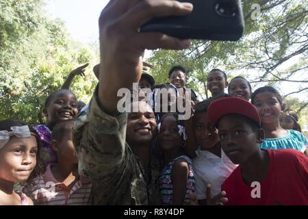 TRUJILLO, Honduras (Feb. 27, 2017) - Equipment Operator 2nd Class Elijah Godbold, a native of Augusta, Ga., Assigned to Construction Battalion Maintenance Unit (CBMU) 202, takes a photo with host nation children during a U.S. Band concert during Continuing Promise 2017 (CP-17) in Trujillo, Honduras.  CP-17 is a U.S. Southern Command-sponsored and U.S. Naval Forces Southern Command/U.S. 4th Fleet-conducted deployment to conduct civil-military operations including humanitarian assistance, training engagements, medical, dental, and veterinary support in an effort to show U.S. support and commitme Stock Photo