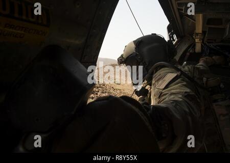 A HH-60 Pavehawk aerial gunner, from the 303rd Expeditionary Rescue Squadron, checks the altitude of the aircraft during a training flight March 2, 2017, around Camp Lemonnier, Djibouti. The 303rd EQRS are part of the 449th Air Expeditionary Group Personnel Recovery Task Force, where they conduct continuous personnel recovery activities to enable regional actors to neutralize violent extremist organizations within East Africa and the Arabian Peninsula in order to protect and defend United States interests. Stock Photo