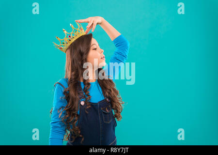 Feels like queen. Kid wear golden crown symbol of princess. Every girl dreaming to become princess. Lady little princess. Girl cute baby wear crown while stand blue background. Childhood concept. Stock Photo