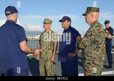 Lt. Patrick Frost, a combat systems officer aboard the U.S. Coast Guard Cutter Munro (WMSL 755), briefs Adm. Harry Harris, Jr., commander, U.S. Pacific Command, Rear Adm. Vincent Atkins, commander, Coast Guard 14th District and Lt. Gen. David Berger, commander, U.S. Marine Corps Forces, Pacific, about ship systems in Honolulu, March 8, 2017. Munro is the sixth of nine planned National Security Cutters and the fourth to be homeported on the on the West Coast in Alameda, Calif. Stock Photo