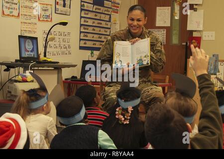 Pfc. Elise M. Fuentes, a military police with 218th Military Police Company, 716th MP Battalion, 101st Airborne Division (Air Assault) Sustainment Brigade, 101st Abn. Div., shows first grade students the illustrations in a book, March 2, 2017, during Read Across America Day at Marshall Elementary School on Fort Campbell, Kentucky. Marshall Elementary School celebrated the 20th anniversary of Read Across America by inviting Soldiers from 716th MP Bn. to read to the elementary students and by putting together a production of Dr. Seuss’s “The Cat in the Hat.” Stock Photo