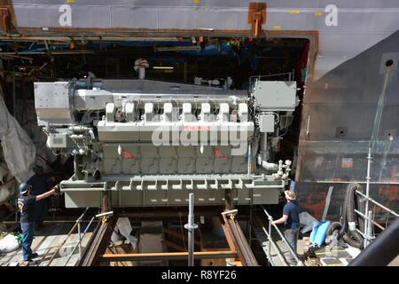 The replacement engine for USS Freedom (LCS 1) is moved into position through a precise cut in the side of the hull. Stock Photo