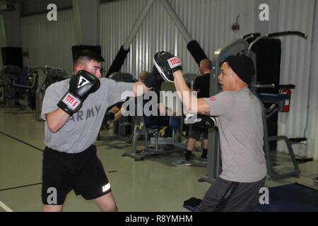 Sgt. Marcos Benitez (left), an M1 Abrams gunner with 1st Battalion, 8th Infantry Regiment, 3rd Armored Brigade Combat Team, 4th Infantry Division, lands a left jab while sparring with Sgt. 1st Class Joel Vallete, the battalion’s signal section chief, at a gymnasium at Mihail Kogalniceanu Air Base, Romania, March 8, 2017. Despite being deployed 6,500 miles from home station Fort Carson, Colorado, for Operation Atlantic Resolve, Benitez and Vallete have brought their training forward and have encouraged other service members stationed at the Romanian base to join in the training. Stock Photo