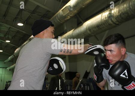 Sgt. Marcos Benitez (right), an M1 Abrams gunner with 1st Battalion, 8th Infantry Regiment, 3rd Armored Brigade Combat Team, 4th Infantry Division, spars with Sgt. 1st Class Joel Vallete, the battalion’s signal section chief, at a gymnasium at Mihail Kogalniceanu Air Base, Romania, March 8, 2017. Despite being deployed 6,500 miles from home station Fort Carson, Colorado, for Operation Atlantic Resolve, Benitez and Vallete have brought their training forward and have encouraged other service members stationed at the Romanian base to join in the training. Stock Photo