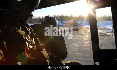 Sgt. Ty Morgan (left) and Cpl. Landon Cheek (center) keep watch out the back of a UH-1Y Venom as it takes off to conduct night-time cold weather operations aboard Fort Drum, N.Y., March 17, 2017. Marines assigned to Marine Light Attack Helicopter Squadron 269, Marine Aircraft Group 29, 2nd Marine Aircraft Wing, conducted close air support at night with live ordnance to simulate real world operations in a forward position. Morgan and Cheek are crew chiefs with HMLA-269. Stock Photo