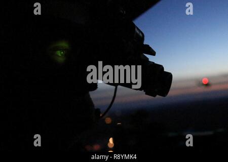 Cpl. Landon Cheek uses his night vision goggles to keep watch out the back of a UH-1Y Venom during night-time cold weather operations aboard Fort Drum, N.Y., March 17, 2017. Marines assigned to Marine Light Attack Helicopter Squadron 269, Marine Aircraft Group 29, 2nd Marine Aircraft Wing, conducted close air support at night with live ordnance to simulate real world operations in a forward position. Cheek is a crew chief with HMLA-269. Stock Photo