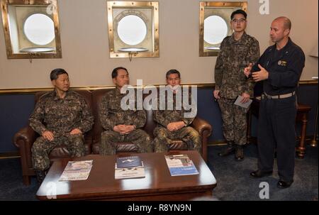 WATERS EAST OF THE KOREAN PENINSULA (March 20, 2017) Rear Adm. Jim Kilby, commander, Carrier Strike Group 1, right, speaks to Gen. Jang, Jun Gyu, chief of staff of the Republic of Korea Army, left, Adm. Um, Hyun Seong, the Republic of Korea chief of naval operations, middle left, and Gen. Jeong, Kyeongdoo, chief of staff of the Republic of Korea Air Force, middle right, in the commanding officer’s in-port cabin aboard the aircraft carrier USS Carl Vinson (CVN 70). The Carl Vinson Carrier Strike Group is on a regularly scheduled Western Pacific deployment as part of the U.S. Pacific Fleet-led i Stock Photo