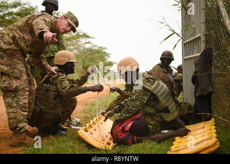 U.S. Army Capt. Brandon Resor with Combined Joint Task Force-Horn of Africa’s (CJTF-HOA), 418th Civil Affairs Battalion, directs Uganda People’s Defense Force (UPDF) soldiers assigned to Ugandan Battle Group 22, as they prepare a simulated casualty for transport during a medical exercise at Camp Singo, Uganda, March 3, 2017. CJTF-HOA members assisted UPDF soldiers assigned to Ugandan Battle Group 22 to employ skills acquired from their predeployment training such as nine-line medical evacuation, combat lifesaving techniques and casualty extraction. Stock Photo