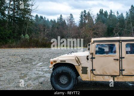 A high mobility multipurpose wheeled vehicle (HMMWV) sits parked in front of Sequalitchew Lake on Joint Base Lewis-McChord, Washington, March 11, 2017. Soldiers from the 301st Maneuver Enhancement Brigade went through a series of maneuver and mobility exercises to ensure deployment readiness and demonstrate the brigade’s ability to command and control in a tactical environment. Stock Photo