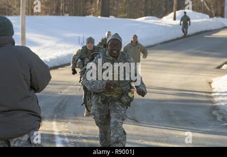 U.S. Army Sgt. Yolande Allen, musical performance professional, 40th Army Band, Garrison Support Command, Vermont National Guard, runs the final stretch of the 10-kilometer ruck march during the Vermont Best Warrior Competition at Camp Ethan Allen Training Site, Jericho, Vt., March 19, 2017.  During the three-day Best Warrior Competition, elite soldiers selected by their units are tested by board interviews, physical fitness tests, written exams, and warrior tasks relevant to today’s operating environment. Stock Photo