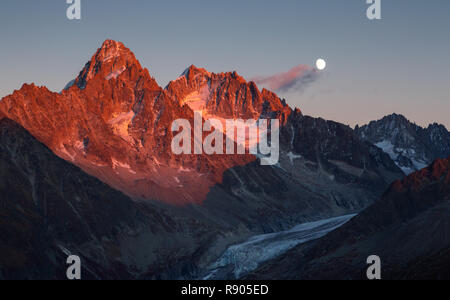 The last, warm sunlight on mountain peak Aiguille D'Argentiere during moonrise. Chamonix, France. Stock Photo