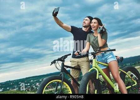 Happy couple with bicycle taking selfie by smartphone outdoors Stock Photo