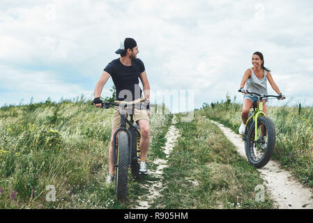 Don't fall behind. The young man on the bike overtakes the attractive woman Stock Photo
