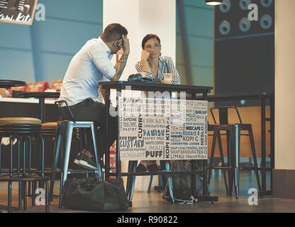 Doha, Qatar - December 9, 2018: beautiful young couple sitting in an airport cafe. Interracial couple talking in coffee shop. Couple sitting at table  Stock Photo