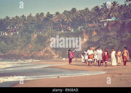 Kerala, India - Nov 30, 2017: Indian family - womans, mans and childs in traditional clothes taking a walk at beautiful sunny morning at Varkala beach Stock Photo