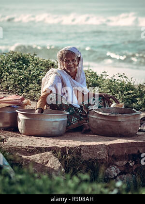 Varkala, Kerala, India – November 30, 2017: Unidentified Indian rural old woman with fishis on beach in Varkala. Daily lifestyle in rural area in Sout Stock Photo