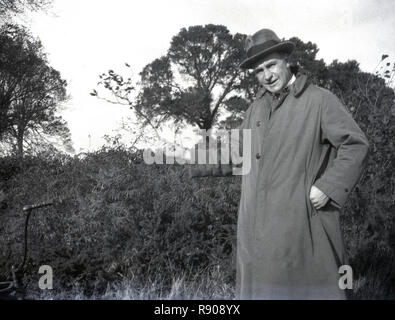 1930s, historical, a gentleman standing outside in his trench raincoat and wearing a trilby hat. Stock Photo