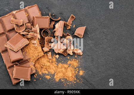 Broken chocolate pieces and chocolate shavings on a dark background. Top view with copyspace for your text. Stock Photo