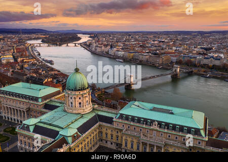 Budapest, Hungary - Aerial view of Buda Castle Royal Palace with Szechenyi Chain Bridge, Parliament and colorful clouds at golden sunrise Stock Photo