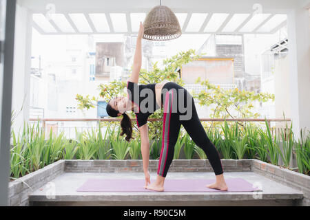 Young asian woman in relaxation stretching position on her balcony floor Stock Photo