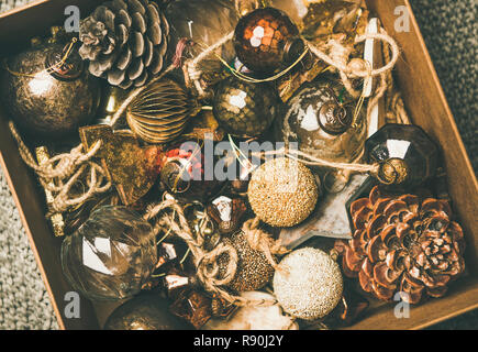 Christmas or New Year preparation. Flat-lay of vintage Christmas tree decoration toys, balls and pine cones in wooden box over grey knitted blanket ba Stock Photo
