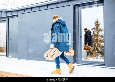 Portrait of a man in winter clothes with a snow shovel near the modern  house in the mountains Stock Photo - Alamy