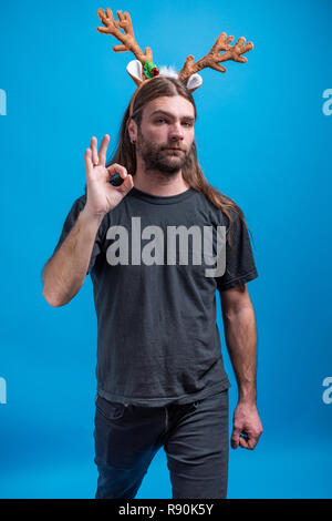 Male wearing raindeer hair band with straight face displaying ok sign. Single person shot in studio Stock Photo