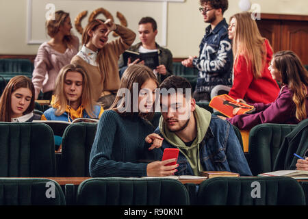 The group of cheerful students sitting in a lecture hall before lesson. The education, university, lecture, people, institute, college, studying, friendship and communication concept Stock Photo