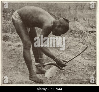 Vintage photograph of Ancient agriculture, a man of using a primitive hoe. Nigeria, early 20th Century Stock Photo