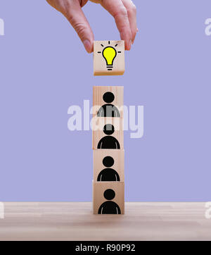 Teamwork brings the idea, symbolized by a stack of cubes with people icons Stock Photo