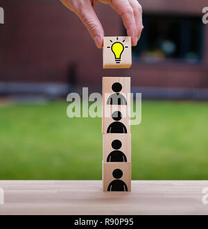 Teamwork brings the idea, symbolized by a stack of cubes with people icons Stock Photo