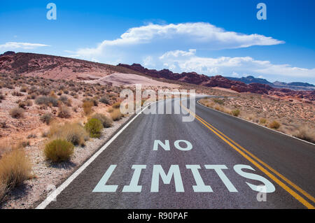 The text 'NO LIMITS' written on a empty road in the desert of Nevada before the street turns right Stock Photo